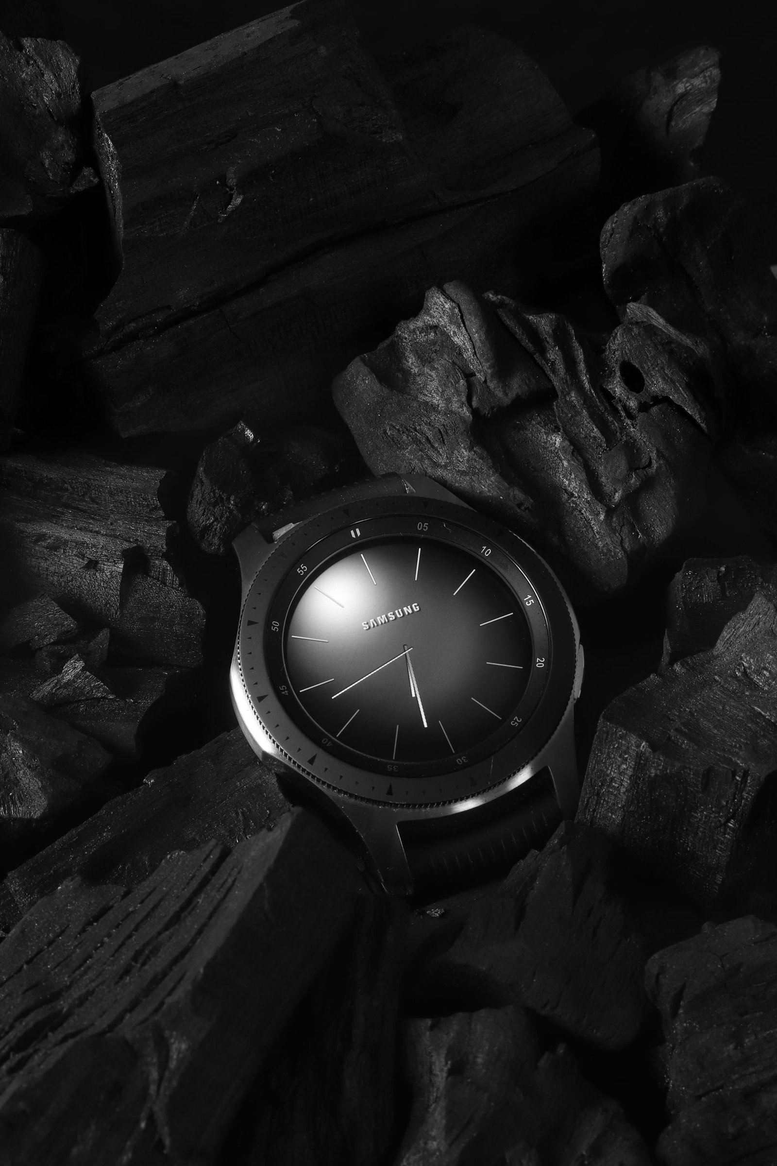 Black and white samsung watch on charcoal, emphasizing precision and elegance.