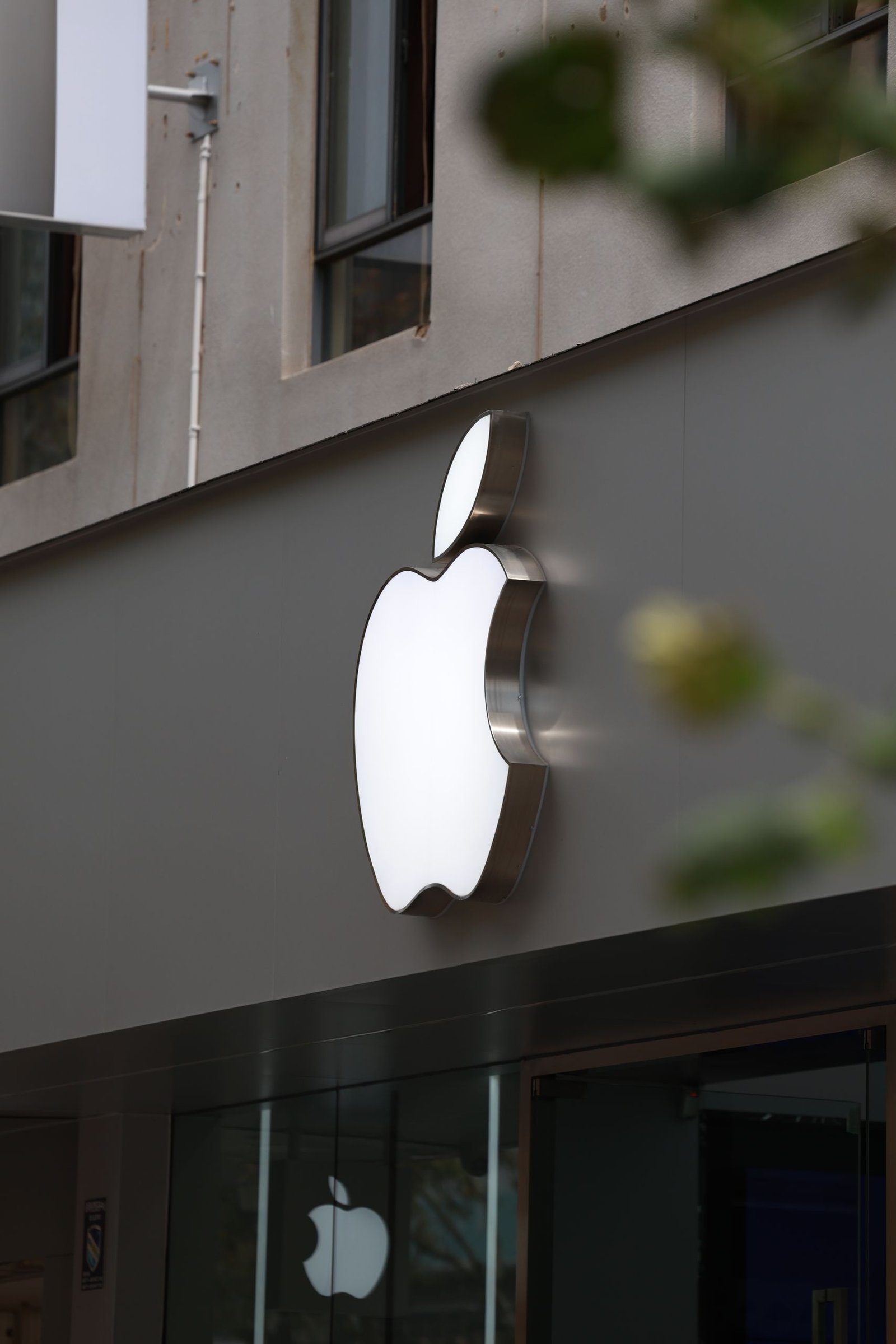 Close-up of Apple Store exterior featuring the illuminated logo prominently displayed.